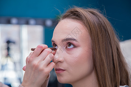 化妆品摄影把化妆师的手画得像一个顾客女孩的眼睛一样贴近背景