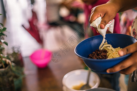 一名拉丁女性在一盘大米和豆子上服酸奶油的图片