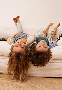 即使倒立也依然无聊 两个年幼的孩子躺在沙发上 头悬在沙发边缘的画像图片