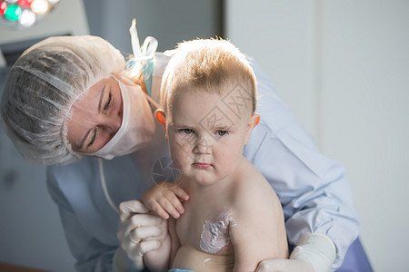 一个小男孩护士治疗烧伤 医院里的一个孩子受伤了 医生治疗婴儿 小医院病人疾病伤害衣服面具门诊部医疗办公室拥抱护理款待男生图片
