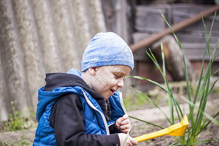 一个孩子正在种植花园 他手里拿着一个孩子的耙子 一个小园丁正在花坛里种植物 孩子手中的园艺工具水仙乐趣农场婴儿工作家庭后院土壤绣图片
