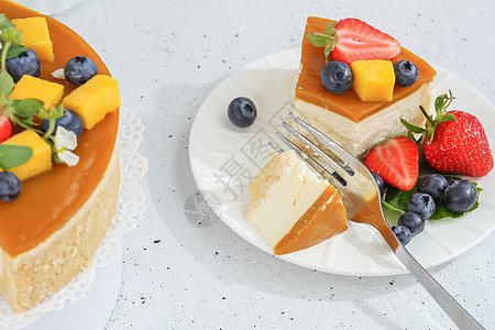 一块芝士蛋糕和芒果放在盘子上 一个茶叉装饰着浆果和灰色背景的鲜花 健康的食物奶制品味道糕点美食甜点美味蛋糕早餐奶油餐厅图片