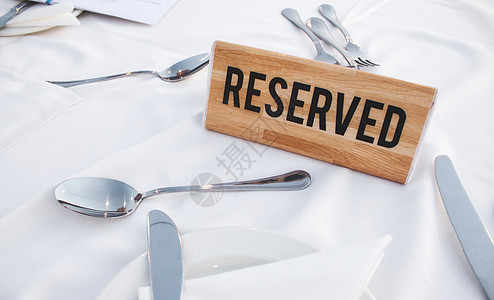 餐桌上的木质保留牌 配有白桌布和闪亮的餐具图片
