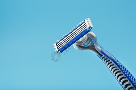蓝色背景上新的剃须机的刀片润滑剂刮胡子金属男人配饰机器塑料剃须刀刀刃工作室图片