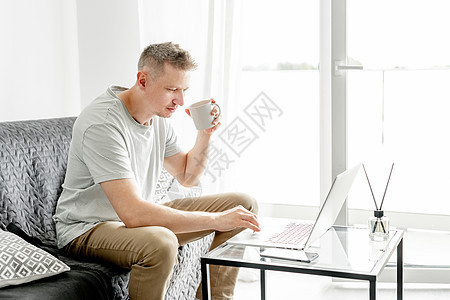 英俊的年轻人在笔记本电脑上工作成人男性工作者白色客厅商业自由职业者技术办公键盘图片