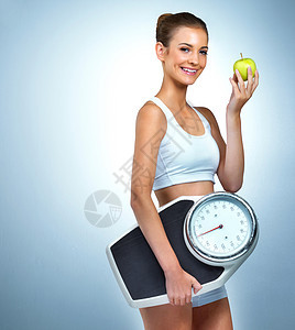 一个有健康意识的年轻女人的肖像 冒充着苹果和在工作室里的一个比例表 她很危险成人成年人姿势饮食裁剪水果幸福绿色女性微笑图片