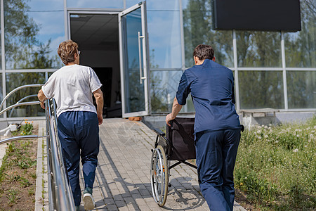 病人和护士在院子里散步后在诊所转过身去健康高清图片素材