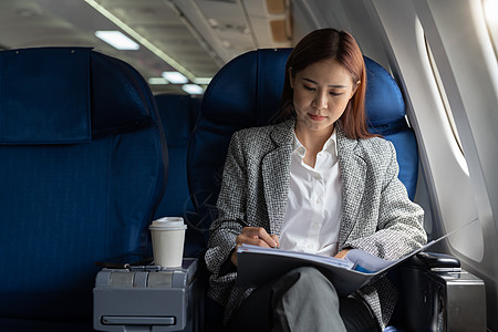 亚裔女性创业者从事书面工作财务报告 坐飞机近窗边的飞机窗口图片