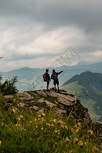 徒步山有两个人站在山悬悬崖上 其中一人指着远处的距离背景