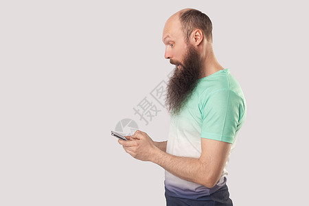 灰色背景的秃头男子的情感胡须肖像手机震惊男人中年白色男性胡子惊喜优胜者绿色图片