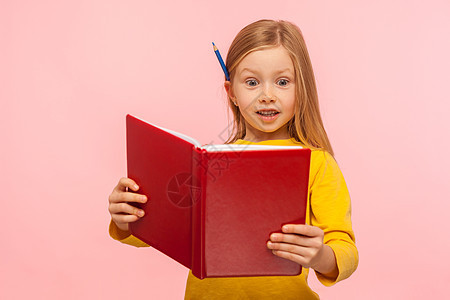 带着铅笔的聪明小女孩 在耳后读着大书 惊讶地表达图片
