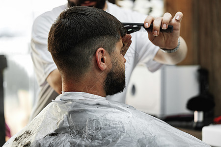 理发师给在理发店坐在椅子上 长胡子的男人理发头发商业客户成人职业顾客服务男性沙龙发型图片