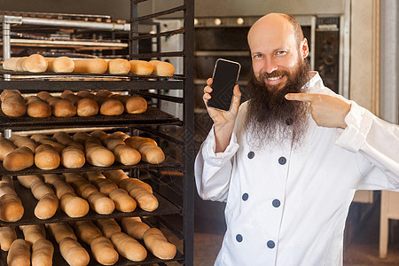 在面包店穿白制服的贝克人男性工厂面包师手指胡须手机服务生产职场货架图片