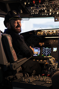 微笑的男机长在指挥板下驾驶飞机的肖像图片