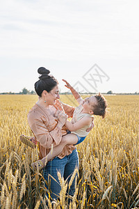母亲和婴儿在小麦田上行走的幸福家庭男性孩子闲暇父母女性男生父亲女士乐趣场地背景图片