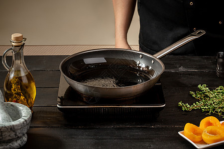 木制桌上有橄榄油的煎锅最佳景色厨师车工厨房金属油炸磨损早餐滚刀气体柜台图片