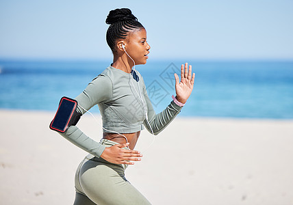 健康活跃的非洲裔美国女性通过耳机听音乐 独自在沙滩上跑步锻炼 专注于黑人运动员训练 锻炼和使用手机跟踪进度海滩运动时间身体技术成图片