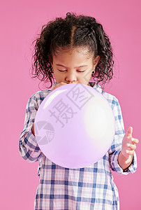 一个漂亮的混血小女孩 一头卷发 在工作室的粉红色复制空间背景下吹气球 非洲儿童在玩乐的同时看起来很满足图片