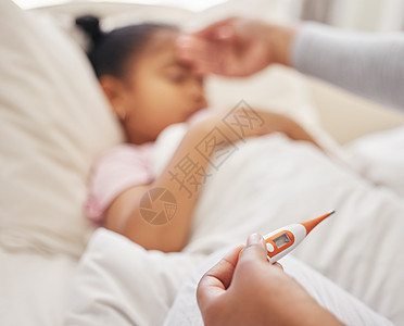 生病的小女孩躺在床上 她的母亲用温度计测量她的体温 混血父母感觉女儿的额头 西班牙裔儿童在母亲检查发烧时感到不适和睡觉图片