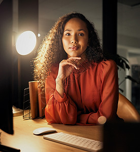 你必须愿意为之努力 一个自信的年轻女商务人士晚上在办公室工作时坐在办公桌前的画像图片