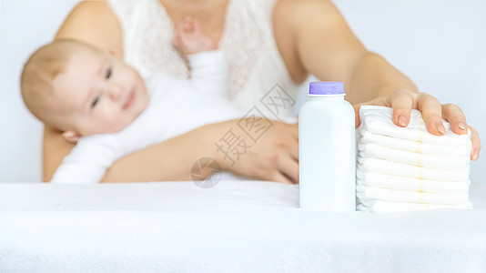 母亲在轻背景上改变婴儿尿布 有选择的焦点桌子幸福婴儿期说谎皮肤父母男生乐趣新生女士图片