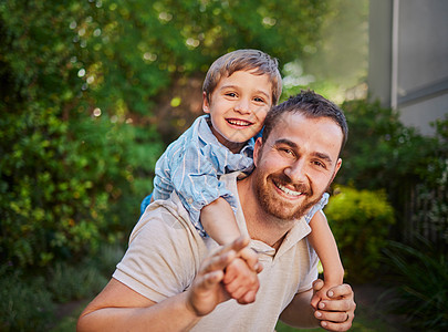 快乐的白人父子在外面玩得很开心 无忧无虑的男人背着兴奋的儿子在花园里搭便车 单身父亲与孩子共度美好时光图片