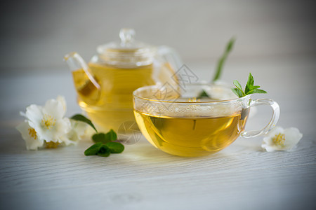 含有茉莉茶和鲜花的杯子茶碗桌子饮料花瓣玻璃植物食物草本植物香气生活图片