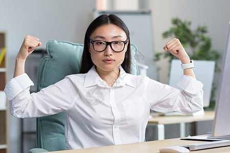 手臂女一位年轻美丽的亚洲女商务人士的肖像 她亲手展示出她的坚强力气背景