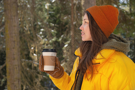 女孩在冬季森林喝热茶或咖啡 用纸杯季节冻结衣服公园杯子假期女性雪花手套女士图片