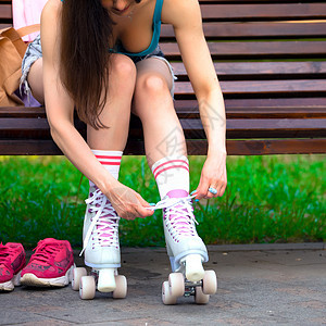 女性滑冰者在公园的长凳上绑着溜冰鞋鞋带刀片长椅齿轮滑冰乐趣运动装溜冰者冰鞋女孩图片