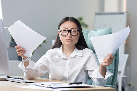 最后期限正在燃烧 年轻的亚洲女商务人士很担心 拿着文件坐在办公室里图片