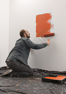 涂有橙色油漆的男性房主绘画墙图片