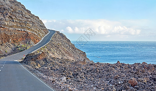 拉帕尔马岛山区公路 沿着海边蜿蜒的道路驶向悬崖顶 西班牙海岸观光 弯曲的海滨路线 蓝天多云 背景是大海图片