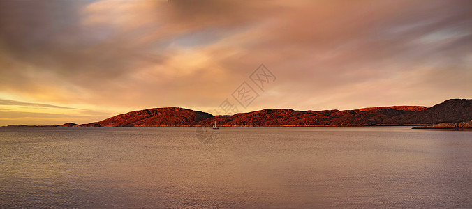 一座山附近的远海景观 水中有一艘小帆船 阴天日落时 海洋 海滩或大湖 远处有一艘船 靠近户外的一座小山图片