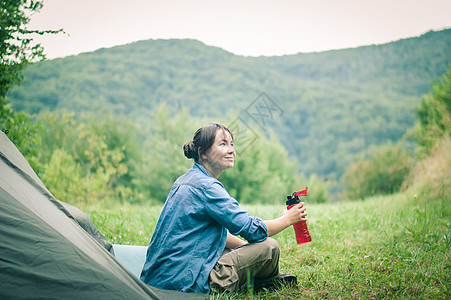 妇女在帐篷附近的山上 是可喜的成人游客闲暇远足者冒险假期幸福背包旅游女孩图片