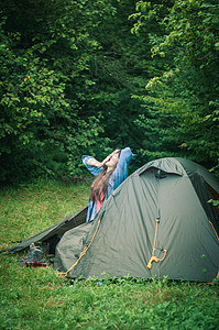 妇女在帐篷附近的山上 是可喜的闲暇旅行享受成人旅游自由冒险森林远足女孩图片