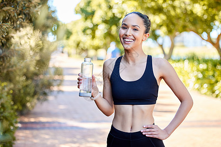 一位健康的年轻混血女性在户外锻炼时休息一下 从瓶子里喝水的画像 快乐的女运动员在跑步和训练后解渴和降温图片