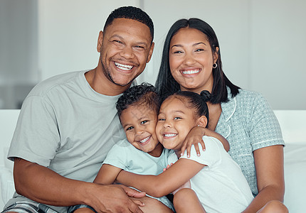 一个快乐的年轻混血家庭的肖像 两个孩子穿着睡衣坐在家里 周末与父母共度时光时 爱的小妹妹和弟弟互相拥抱图片