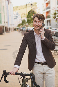 在城市骑自行车的成年男子车辆手机商务工具工人活动运输乐趣街道商业图片