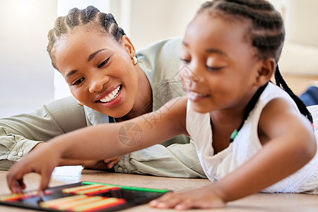 非洲裔美国母亲和女儿一起躺在地板上玩益智玩具 可爱的小女孩一边玩耍 一边与妈妈在家玩耍图片