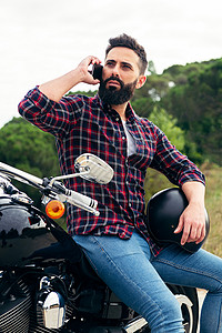 坐在摩托车上的人用手机打电话来图片