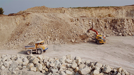 采矿业概念 卡车正在将矿石从露天矿中运出 采石场 露天采矿 矿石开采概念 满载矿石的自卸车驶过矿坑图片
