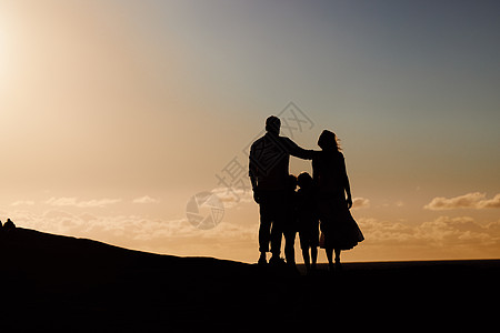 日落时站在外面的剪影夫妇和小孩 一家人在周末享受户外活动和看日落的空闲时间 孩子们和他们的父母在周末图片