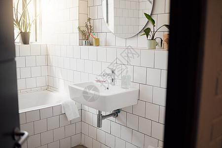 房子里干净整洁的浴室 面盆 浴缸 贴着瓷砖 墙上挂着一面圆镜 干净 卫生 明亮的房间图片