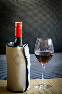红酒瓶加温热冷水器和木底葡萄酒杯图片