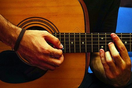 吉他手在弦上弹吉他 把风景拉近木头黑色娱乐歌曲艺术家玩家男人男性手指艺术图片