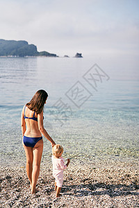 妈妈跟一个小女孩站在沙滩上图片