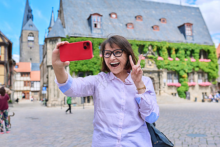 女游客在历史建筑前 在一个古老的欧洲城市自拍自拍房子手机纪念碑女士女性天空地标假期中心建筑学图片