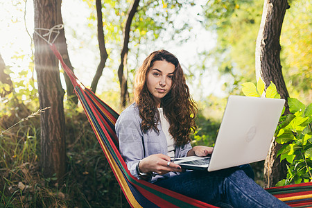 一家人野营躺在吊床上 在笔记本电脑上工作 休息 看电影的美丽年轻自然女性活动女人享受旅行幸福情绪学习技术沉思成人背景