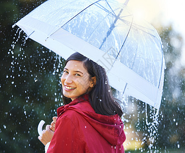 保持干燥 从风暴 一个年轻女人拿着雨伞 在外面的雨中图片